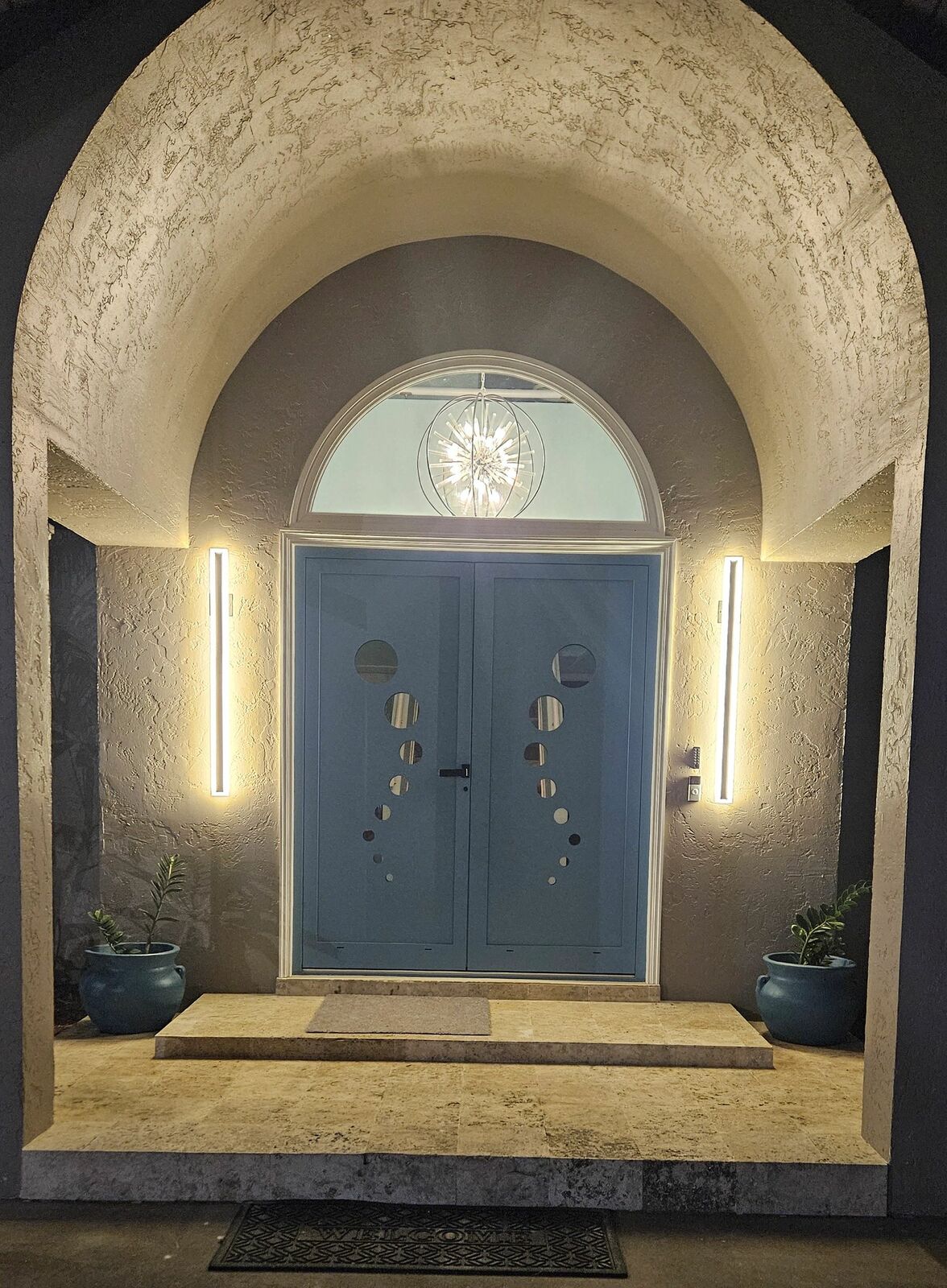 A double front door under an arched entry with new lighting