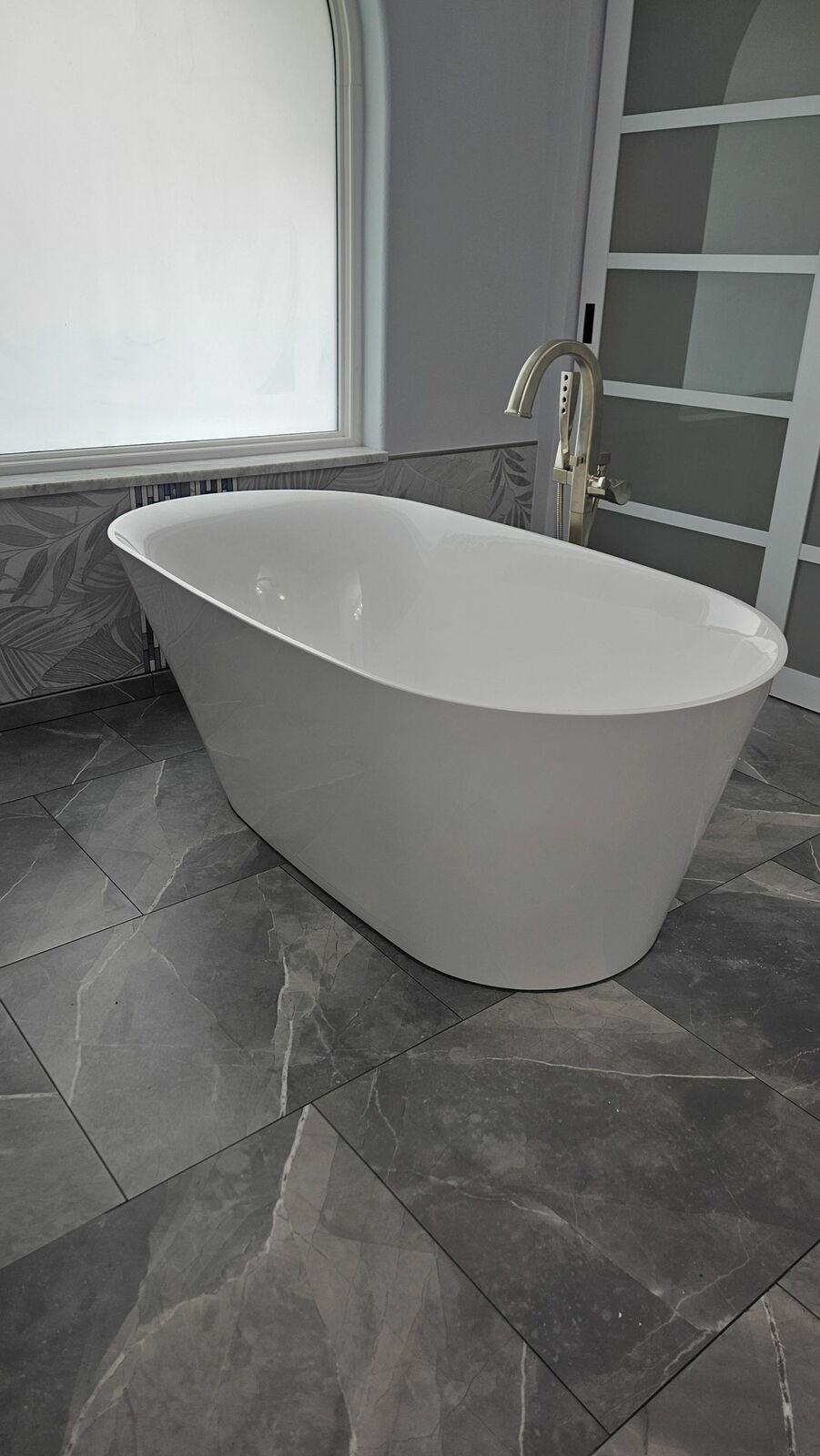 The master bath after: a freestanding white tub on large gray tile