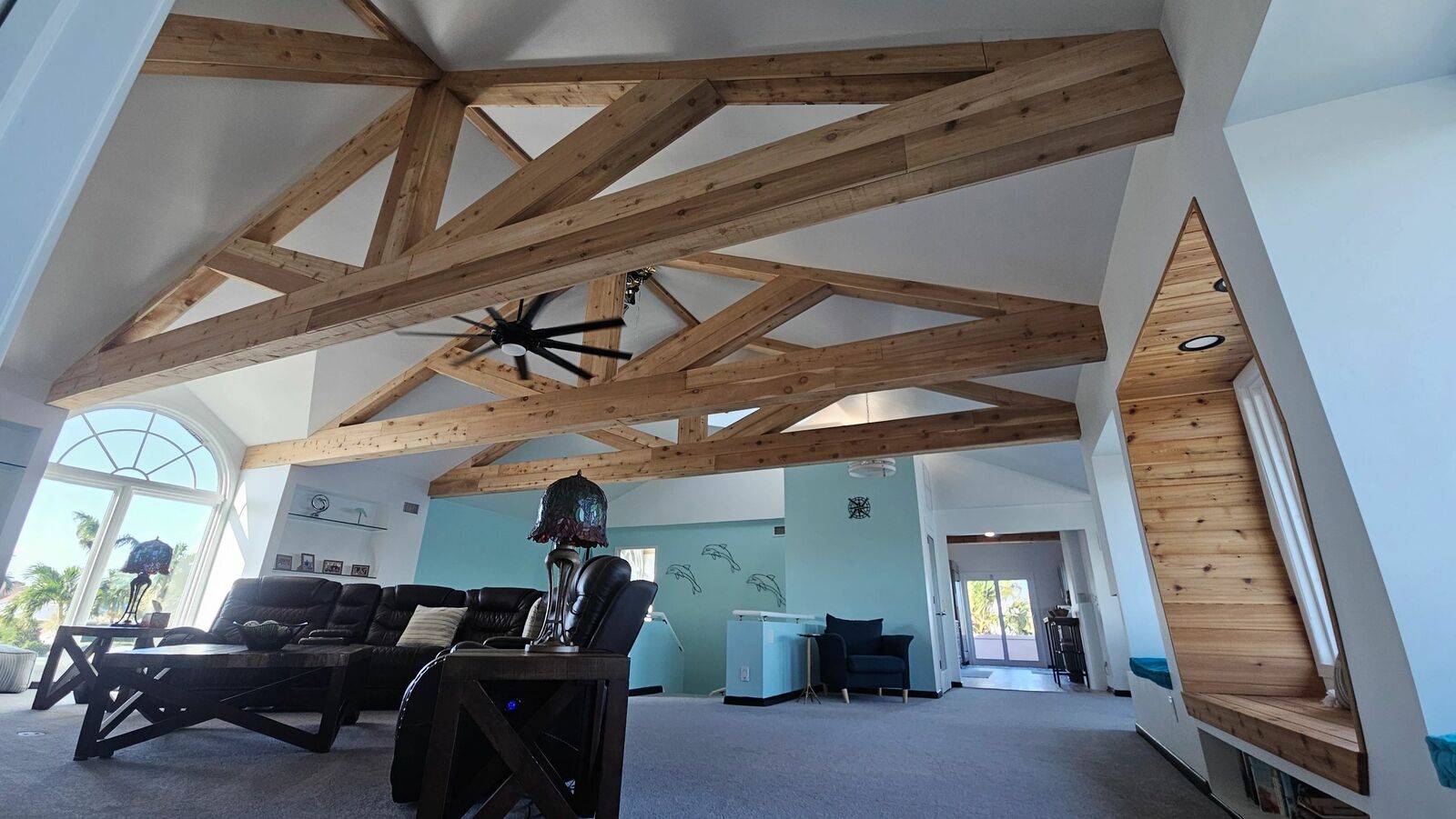 A finished great room with exposed wood trusses and a wall of windows
